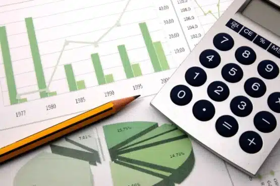 Papel com gráficos e calculadora simulando como calcular o lucro presumido de uma empresa