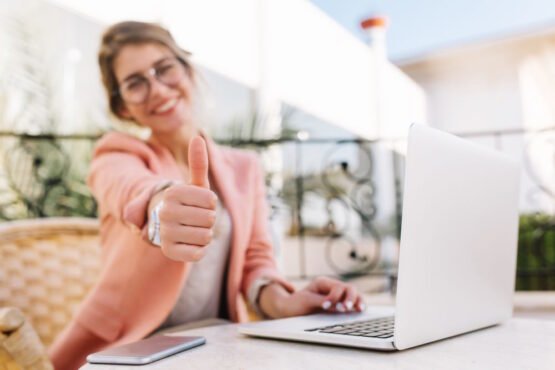 Imagem mostra mulher feliz na frente do computador após realiza o cadastro para tirar carteira do CRC